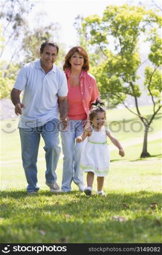 Grandparents walking in park with granddaughter