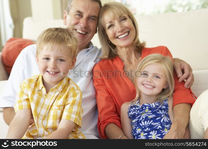 Grandparents With Grandchildren Relaxing On Sofa At Home