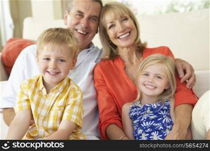 Grandparents With Grandchildren Relaxing On Sofa At Home