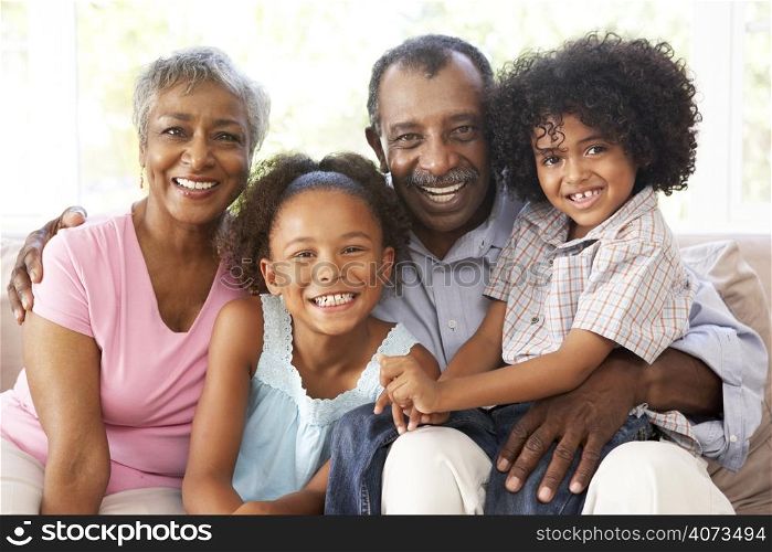 Grandparents With Grandchildren Relaxing On Sofa At Home Together
