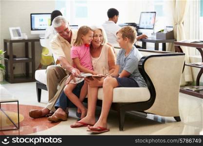 Grandparents With Grandchildren Sitting In Hotel Lobby
