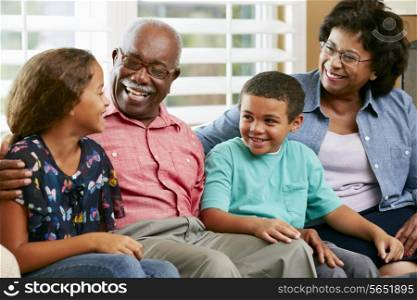 Grandparents With Grandchildren Sitting On Sofa And Talking