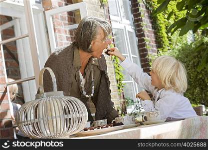 grandson feeding grandma with cake
