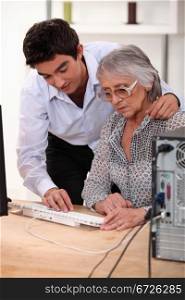 Grandson showing grandmother how to use computer