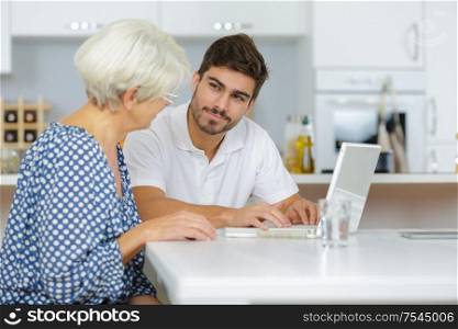 grandson showing senior woman online computer use