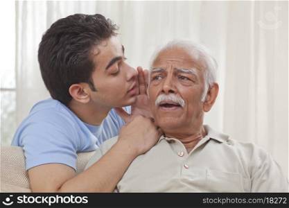 Grandson whispering into grandfather's ear