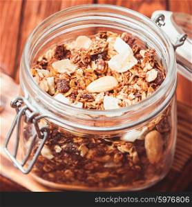 Granola in a jar on the wooden table close up. Granola in jar