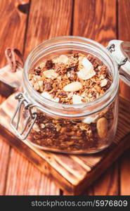 Granola in a jar on the wooden table close up. Granola in jar