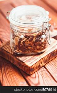 Granola in a jar on the wooden table close up. Granola in jar