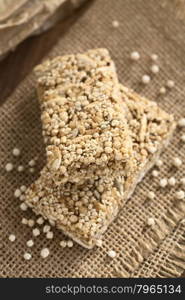 Granola or cereal bars made of popped quinoa, sesame seed, popped rice, sunflower seed, chia and honey, photographed with natural light (Selective Focus, Focus on the front edge of the upper bar)