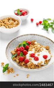 Granola with white plain yogurt and fresh raspberry in a bowl, healthy food for breakfast