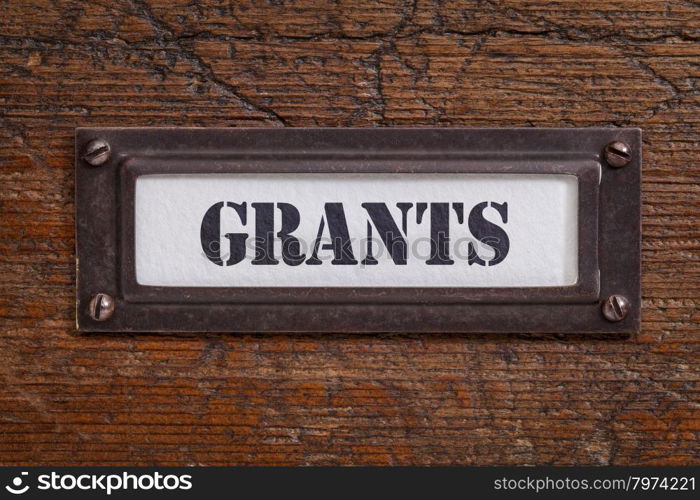 grants - file cabinet label, bronze holder against grunge and scratched wood, financial concept
