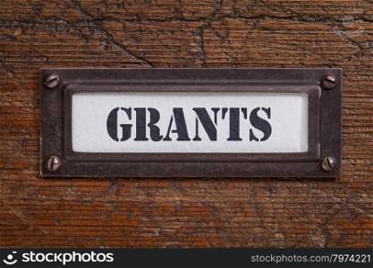 grants - file cabinet label, bronze holder against grunge and scratched wood, financial concept