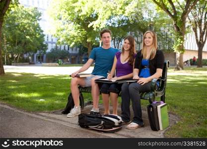 Graoup of three students sitting on a bench studying