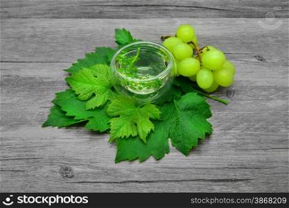 Grape leaves and white wine on a wooden background.
