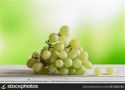 Grape ripe on a wooden table on green background