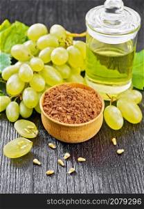 Grape seed flour in a bowl, oil in a jar and green grapes on wooden board background