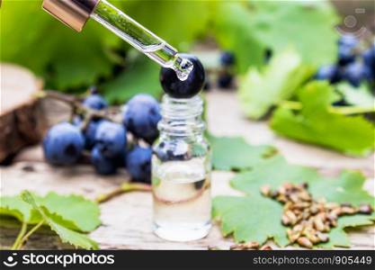 Grape seed oil in a glass jar and fresh grapes on old wooden boards. The concept of SPA, Bio, Eco products.. Grape seed oil in a glass jar and fresh grapes on old wooden boards. The concept of SPA, Eco products.