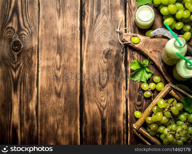 Grape smoothie and a basket of white grapes. On a wooden table.. Grape smoothie and a basket of white grapes.