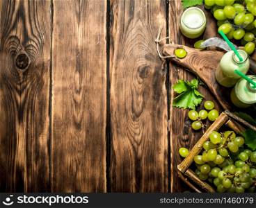 Grape smoothie and a basket of white grapes. On a wooden table.. Grape smoothie and a basket of white grapes.