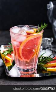 Grapefruit and fresh rosemary gin cocktail with juice, cold summer citrus refreshing drink or beverage with ice