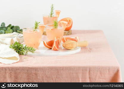 Grapefruit juice with rosemary in glasses on the table. Refreshing summer cocktail.