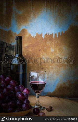 Grapes and wine glasses on a wooden table against a background old rusty.
