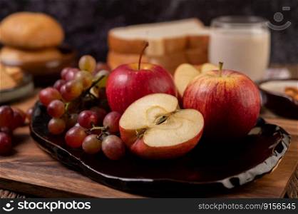 Grapes, apples and bread in a plate on the table. Selective focus.