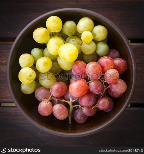 Grapes both white and red in a wooden bowl from overhead