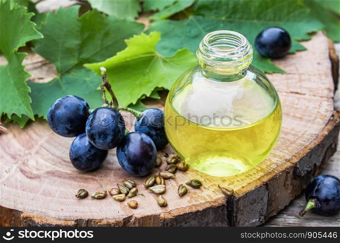 Grapes essential oil in a glass bottle and dice on old wooden boards. Blue grape. Spa, bio, eco products concept.. Grapes essential oil in a glass bottle and dice on old wooden boards. Blue grape. Spa, eco products concept.