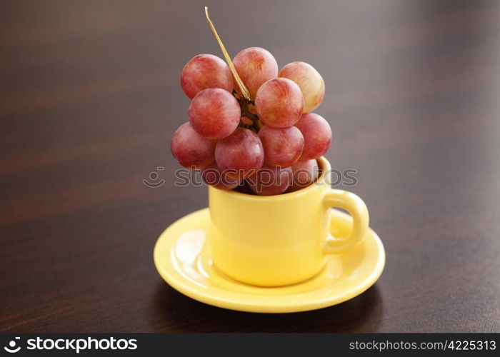 grapes in a cup and saucer on a wooden table