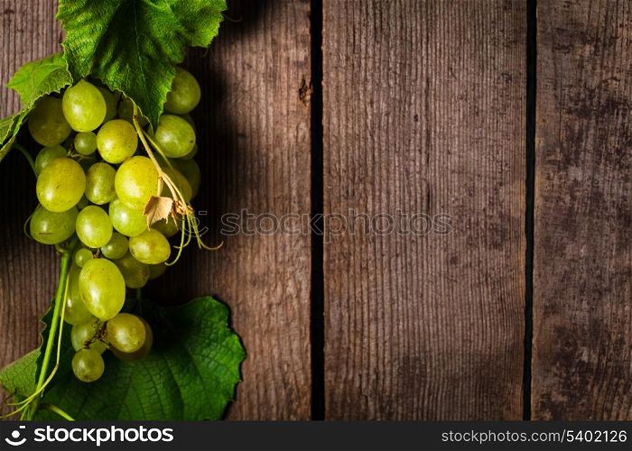 Grapes with leaves on the wood background closeup