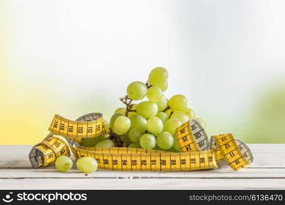 Grapes with yellow measure tape on a wooden table