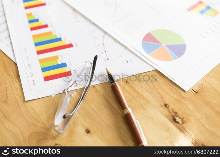 graph and chart analysis paperwork document with eyeglasses and pen on office desk