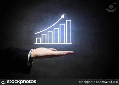 Graph on hand. Hand of businessman on dark background showing glowing business growth concept