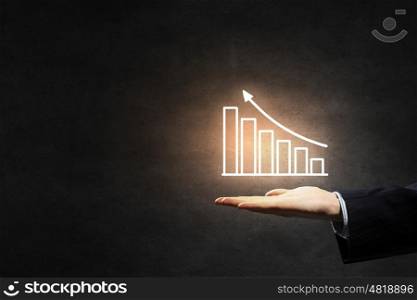 Graph on hand. Hand of businessman on dark background showing glowing business growth concept