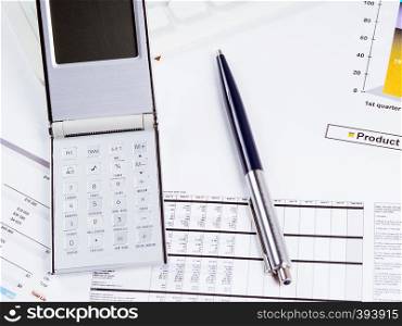 Graphic charts, calculator and pen on the desktop. Calculator, pen on the background of graphic charts