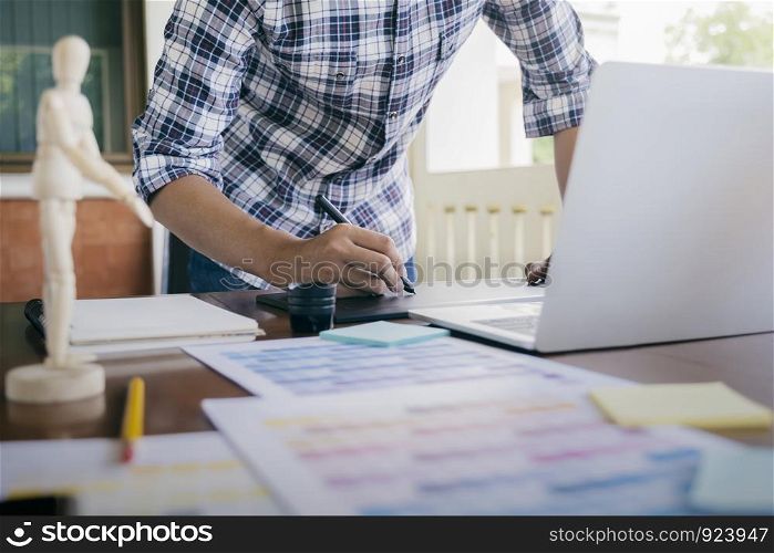 Graphic designer and Photographer working on computer and used graphics tablet.