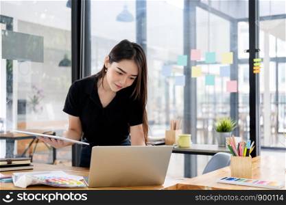 Graphic designer working at her desk in creative studio office.