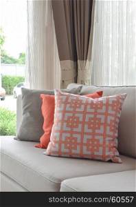 Graphic pattern, orange and gray pillow on beige sofa