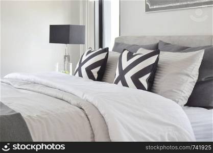 Graphic style pillows on on classic color bedding with black reading lamp