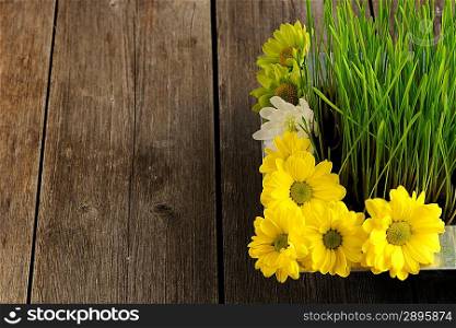Grass and flowers over wooden table