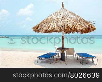 Grass umbrella at the beach on Aruba island at sunset