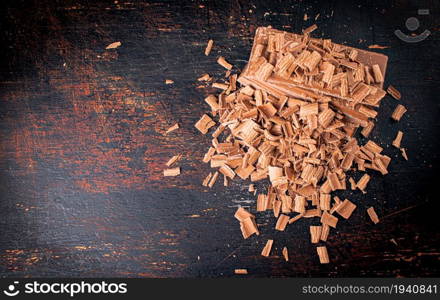 Grated and pieces of milk chocolate. Top view. On a rustic background.. Grated and pieces of milk chocolate. Top view.