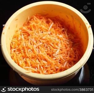 grated carrots in a bowl vegetables salad black background