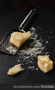 Grated cheese close-up on a dark kitchen table. Chunks of parmegiano cheese on the kitchen table