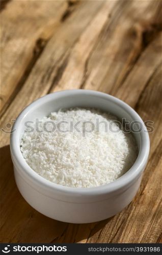 Grated coconut in small on wood, photographed with natural light (Selective Focus, Focus one third into the grated coconut)