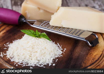 grated parmesan cheese and metal grater on wooden board