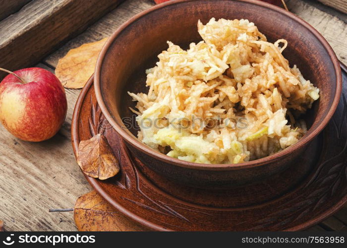 Grated ripe autumn apples in a plate on a wooden old table. Grated ripe apples