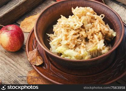 Grated ripe autumn apples in a plate on a wooden old table. Grated ripe apples